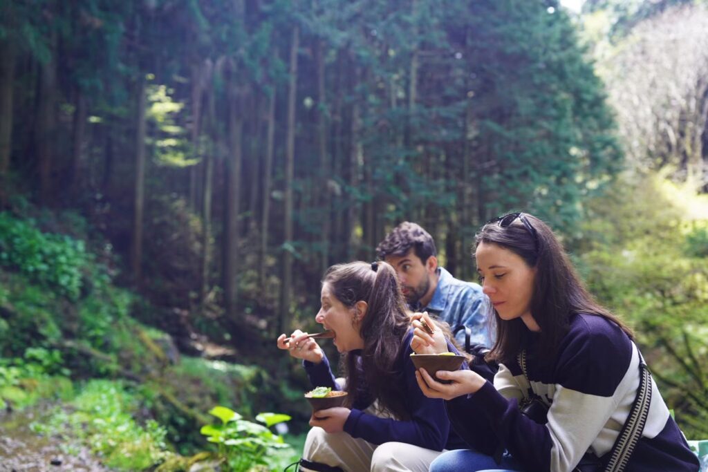 Tour guests enjoying freshly prepared wasabi dishes in the forest during the Wasabi Experience Tour in Okutama