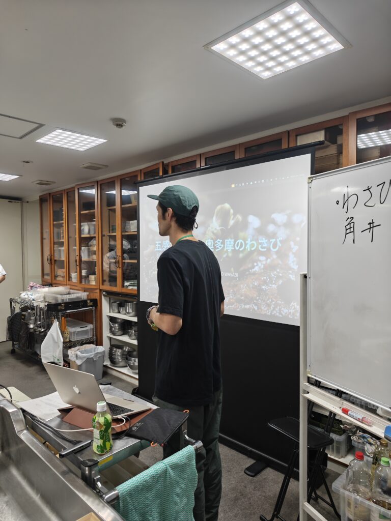 スクリーンに「五感で感じる奥多摩のわさび」を映して授業をするTOKYO WASABIの角井仁